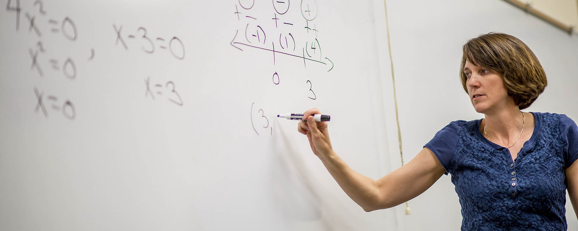 Math professor demonstrating a math problem on the board.